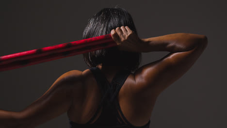 Foto-De-Estudio-De-Vista-Trasera-De-Una-Mujer-Madura-Que-Usa-Ropa-De-Gimnasio-Haciendo-Ejercicio-Con-Palos-De-Escrima-De-Artes-Marciales